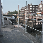 831130 Afbeelding van twee sluiswachters bij de Weerdsluis te Utrecht; op de achtergrond de Stenenbrug over de Vecht.